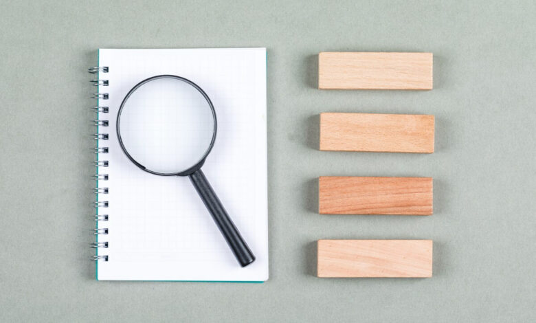 searching-research-concept-with-notebook-magnifier-wooden-blocks-gray-background-top-view-horizontal-image