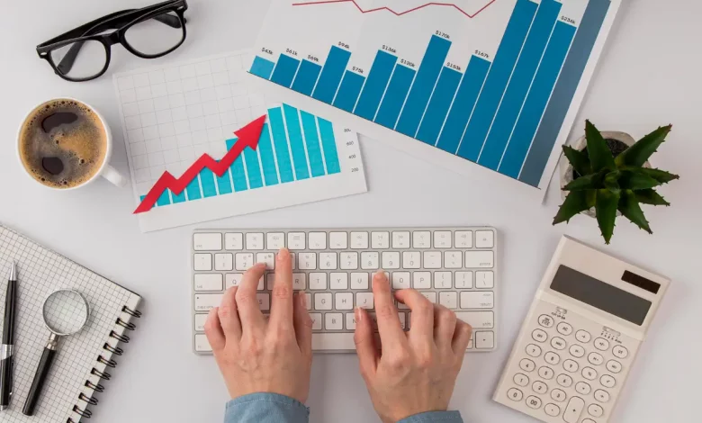 top-view-office-desk-with-growth-chart-hands-using-keyboard